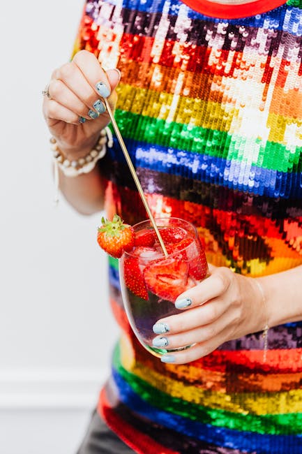 Person in vibrant sequin top holds a glass of strawberry cocktail.
