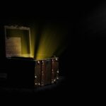 Open wooden chest emitting a mysterious glowing light in a dark room.
