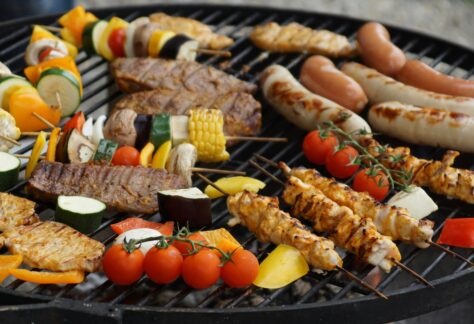 A vibrant assortment of grilled meats, sausages, and vegetables on a barbecue grill.