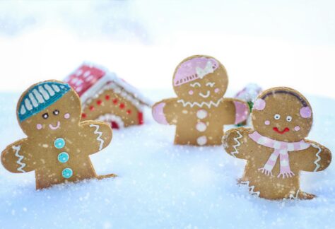 Three gingerbread figures in snow, celebrating a cheerful winter season.