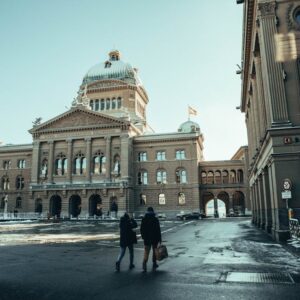 A couple walks in front of the Swiss Parliament Building in Berne, capturing a winter urban scene.