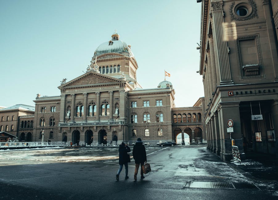 A couple walks in front of the Swiss Parliament Building in Berne, capturing a winter urban scene.