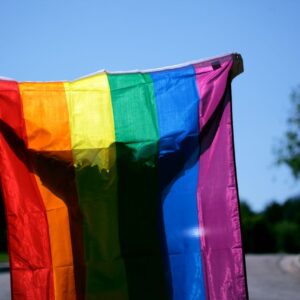un homme portant à bout de bras un drapeau arc-en-ciel