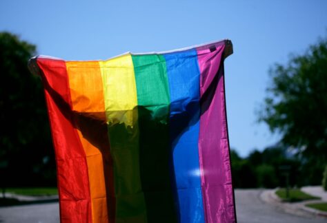 un homme portant à bout de bras un drapeau arc-en-ciel