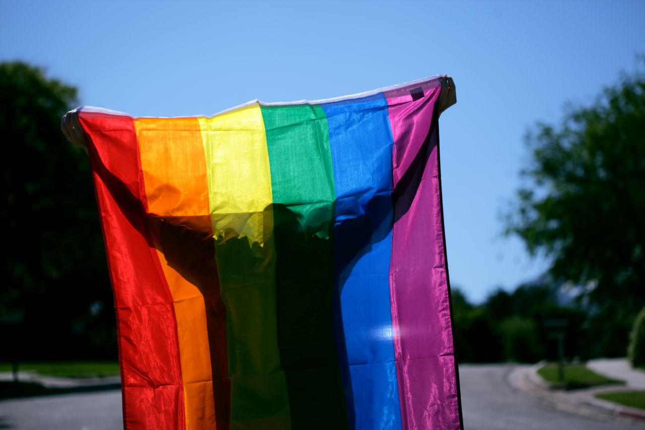 un homme portant à bout de bras un drapeau arc-en-ciel